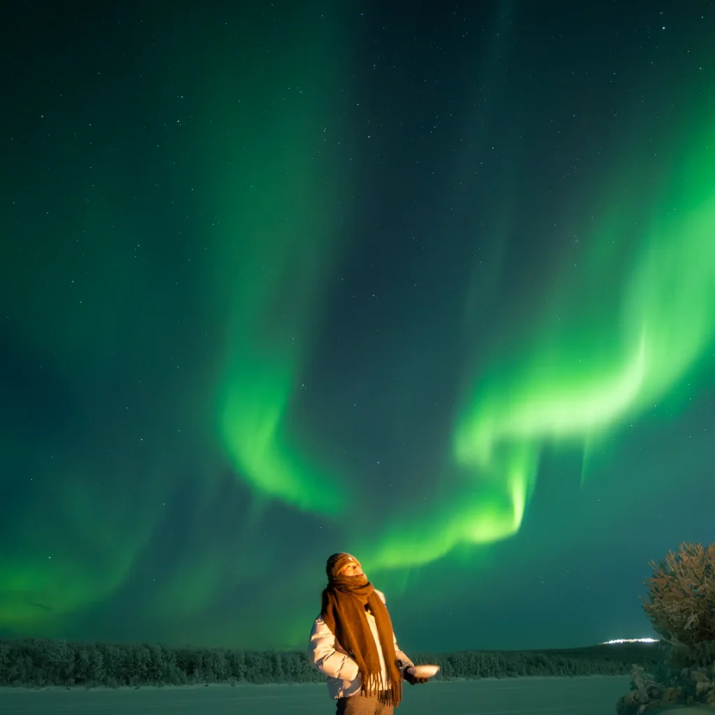 Colorful Northern Lights above a cozy cabin in Lapland, Finland at night