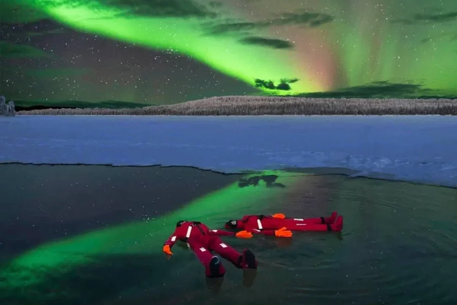 Traveler floating in icy water during a winter tour in Rovaniemi.