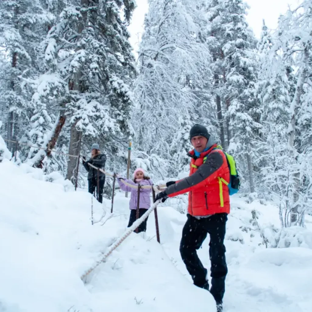 Family winter hiking near frozen icefalls in Korouoma