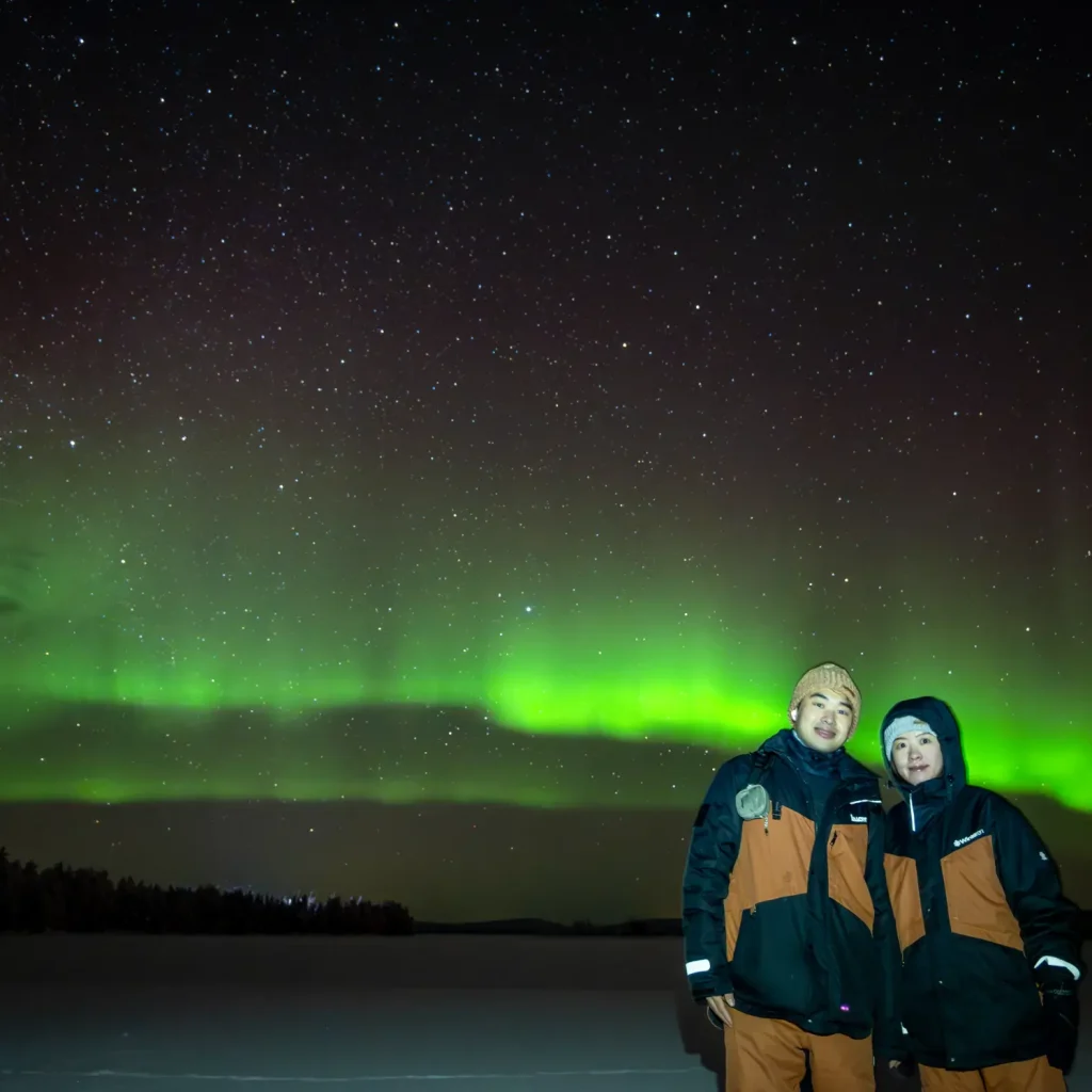 Couple posing beneath the Northern Lights in Finnish Lapland
