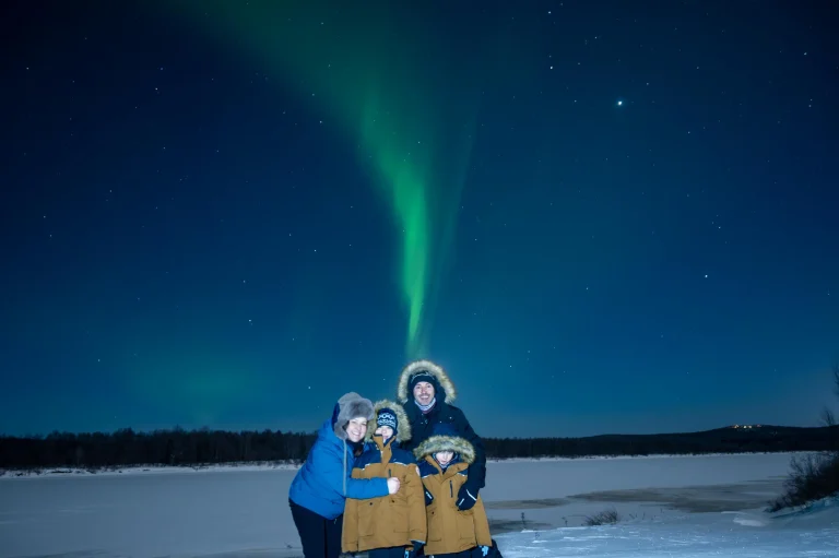 Family enjoying the Northern Lights under a starry Lapland sky